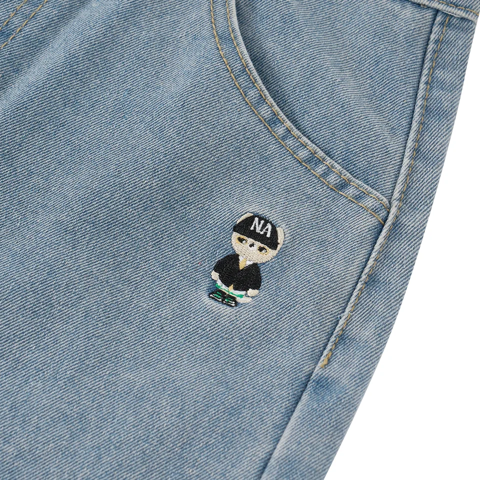 Cận cảnh mascot Nafox thêu trên túi quần denim xanh.